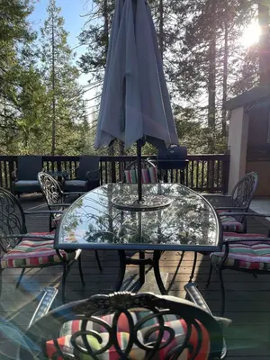 an umbrella sitting on a glass table on a patio at Twain Harte Cabin in Town & Lake access in Twain Harte