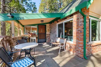 a brick house with a green awning and a patio at Twain Harte Cabin in Town & Lake access in Twain Harte