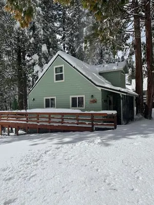 a green house with a wooden fence in the snow at Cabin #4 in Strawberry