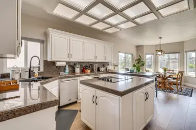 a large kitchen with white cabinets and a table at Private Dock Discovery Bay Vacation Rental! in Discovery Bay