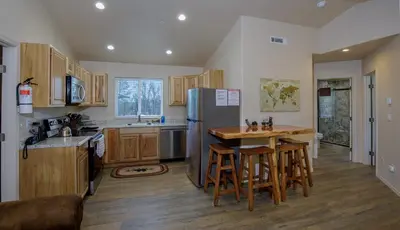 a kitchen with a refrigerator and a table with stools at Bear Paw Cabin new construction near Yosemite in Mariposa