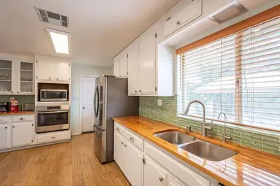 a kitchen with white cabinets and a stainless steel refrigerator at Cherry Cottage 15 min from Yosemite South Entrance in Oakhurst