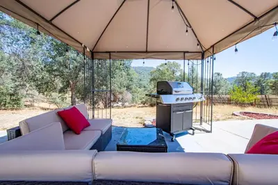 a patio with a couch and a grill in a tent at Cherry Cottage 15 min from Yosemite South Entrance in Oakhurst
