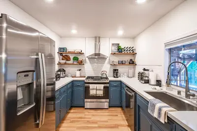 a kitchen with blue cabinets and a stainless steel refrigerator at Sugarpine Trailhead Lodge at Lewis Creek Upper Trailhead just 7 miles from Yosemite in Oakhurst