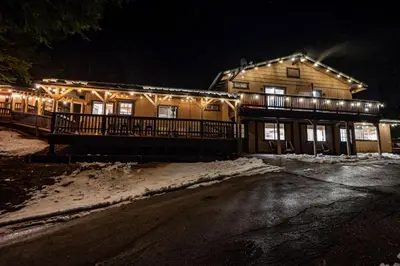 a house with lights on the front of it at night at Sugarpine Trailhead Lodge at Lewis Creek Upper Trailhead just 7 miles from Yosemite in Oakhurst