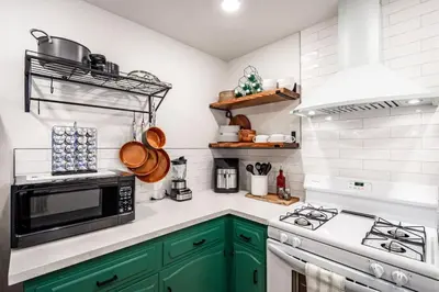 a kitchen with green cabinets and a microwave at Sugarpine Trailhead Lodge at Lewis Creek Upper Trailhead just 7 miles from Yosemite in Oakhurst