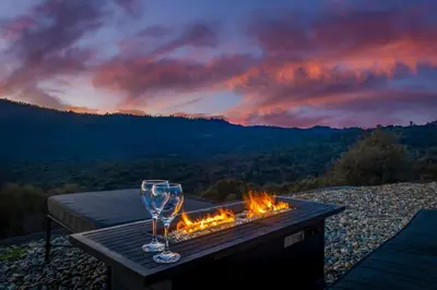 a table with two wine glasses and a fire pit at Fairy Tale 13-acre Sunset Villa at Windy Gap Valley near Yosemite in Ahwahnee