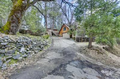 a driveway leading to a house with a stone wall at Lakeside Bear Lodge Studio 9 Mi to Bass Lake! in Bass Lake Annex