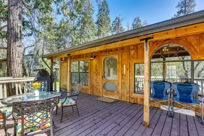 a wooden cabin with a table and chairs on a deck at 9 Mi to Bass Lake Cabin with Fire Pit in Wishon! in Bass Lake Annex