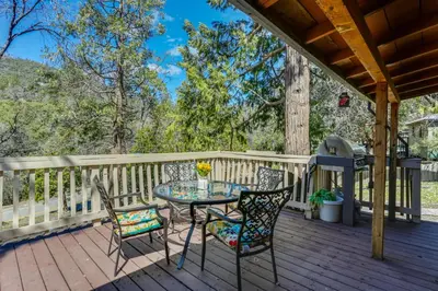 a patio with a table and chairs on a deck at 9 Mi to Bass Lake Cabin with Fire Pit in Wishon! in Bass Lake Annex