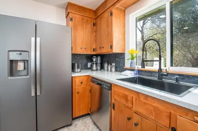 a kitchen with a stainless steel refrigerator and a sink at Buckeye Bungalow w hot tub/firepit/views Pet Friendly in Oakhurst