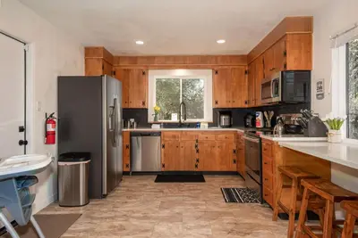 a kitchen with wooden cabinets and a stainless steel refrigerator at Buckeye Bungalow w hot tub/firepit/views Pet Friendly in Oakhurst
