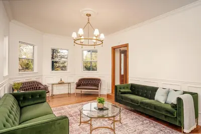 a living room with two green couches and a table at Yosemite Country House sleeps 20 w/ hot tub, firepit, bonus studio in Oakhurst