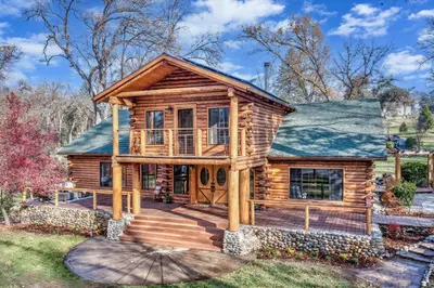 a log cabin with a porch and a deck at Log Cabin sleeps 20 with hot tub, EV Charger, firepit in Ahwahnee