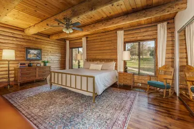 a bedroom with a bed in a room with wooden walls at Log Cabin sleeps 20 with hot tub, EV Charger, firepit in Ahwahnee