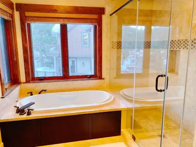 a bathroom with a tub and a glass shower at Luxury Northstar Home| hot tub| walk to ski lifts in Truckee