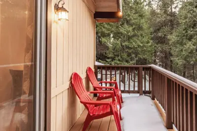 two red chairs sitting on the porch of a house at Red Rock Falls Cabin, 8 miles from Yosemite South Gate, with trailhead, Game Room and HotTub in Oakhurst