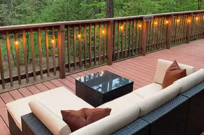 a white couch on a deck with a table and lights at Harte's Desire Cabin - Lake, A/C, Arcade + in Twain Harte