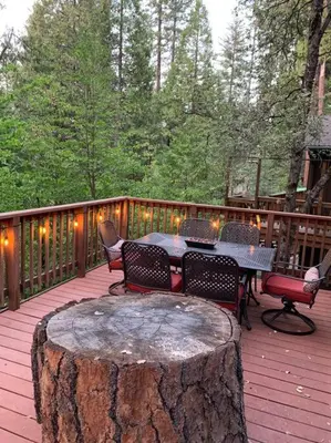 a deck with a table and chairs and a large tree stump at Harte's Desire Cabin - Lake, A/C, Arcade + in Twain Harte