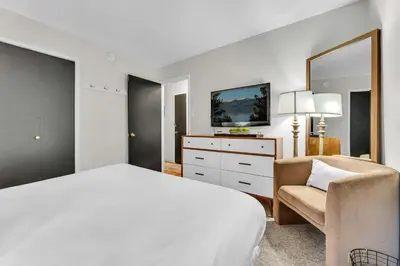 a white bedroom with a bed and a chair at The Rigi Chalet HOA Beach Access Close to town in Tahoe City