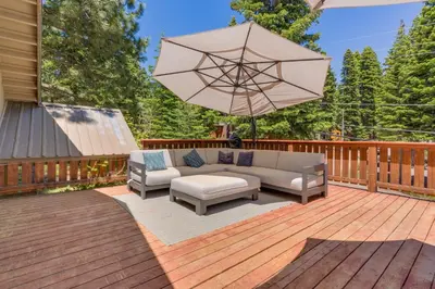 a patio with a couch and an umbrella on a deck at Modern 3BR Tahoe Cabin with Hot Tub in Tahoe City