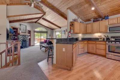an open kitchen with wooden cabinets and a living room at Modern 3BR Tahoe Cabin with Hot Tub in Tahoe City