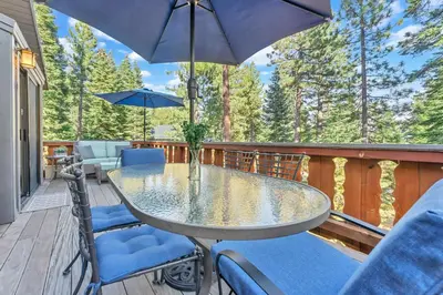 a table and chairs on a deck with an umbrella at The Big Bear Chalet Private Hot Tub in Carnelian Bay