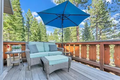 a patio with a couch and an umbrella on a deck at The Big Bear Chalet Private Hot Tub in Carnelian Bay