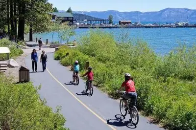 a group of people riding bikes on a path by the water at Mt Airy Cottage Walk to Beach in Tahoe Vista