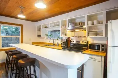 a kitchen with a white counter and bar with stools at Mt Airy Cottage Walk to Beach in Tahoe Vista