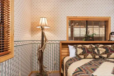 a bedroom with a bed and a floor lamp at Toste Cabin- Spacious 3BR Cabin in East Village! in Shaver Lake