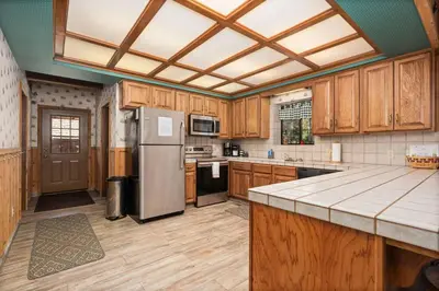 a kitchen with wooden cabinets and a stainless steel refrigerator at Toste Cabin- Spacious 3BR Cabin in East Village! in Shaver Lake