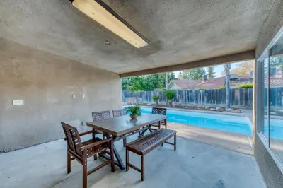 a patio with a table and chairs and a swimming pool at Fig Garden 4BR House W Pool in Fresno