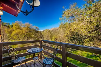 a balcony with chairs and a view of the mountains at Sierra Vista Lookout Lodge with Creek, Waterfall and Waterholes, minutes from Bass Lake and Yosemite South Gate in North Fork