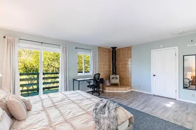 a bedroom with a bed and a desk and windows at Sierra Vista Lookout Lodge with Creek, Waterfall and Waterholes, minutes from Bass Lake and Yosemite South Gate in North Fork