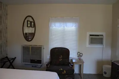a bedroom with a bed and a chair and a window at The Bonnie Inn Unit 1 in San Andreas