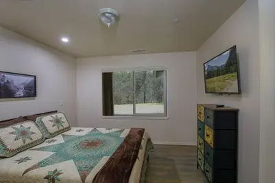 a bedroom with a large bed and a window at Cozy Cub Cabin, brand new home near Yosemite in Mariposa
