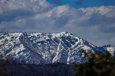 a snow covered mountain with trees on top of it at Cozy Cub Cabin, brand new home near Yosemite in Mariposa