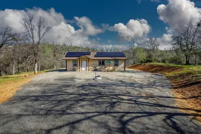 a house with a solar roof on a road at Cozy Cub Cabin, brand new home near Yosemite in Mariposa