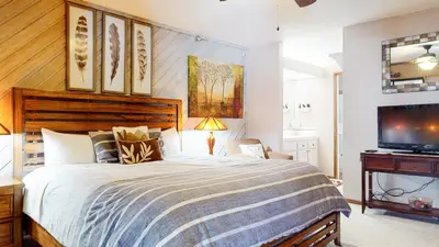 a bedroom with a large bed and a flat screen tv at Aspen Creek #227 condo in Mammoth Lakes