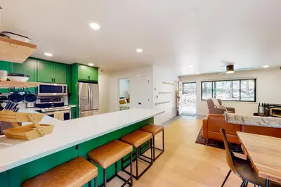 a kitchen with green cabinets and a counter with chairs at Piney Point in Arnold