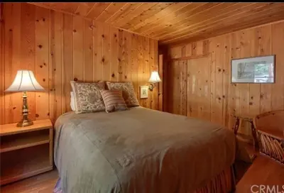 a bedroom with a bed in a room with wooden walls at Uncle Grizz's Cabin...get intouch with nature in Bass Lake Annex