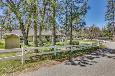 a white fence in front of a house with trees at Oakhurst Vacation Rental Near Hiking and Bass Lake! in Oakhurst